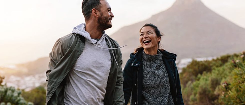 Young couple hiking in the mountains and laughing the whole way