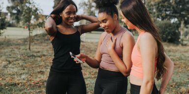 Two women looking together at a cell phone as a symbol for how to successfully start a conversation on a dating app