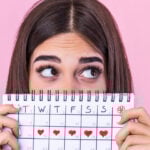 Woman holding a calendar with a date marked for every day that week