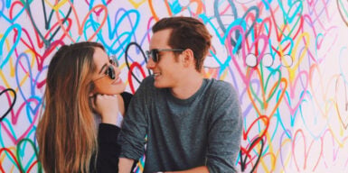 A couple having an intimate moment in front of a wall of hearts