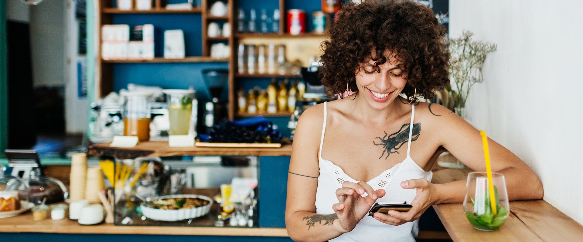 Woman on cell phone in coffee smiles as a symbol for meeting people online