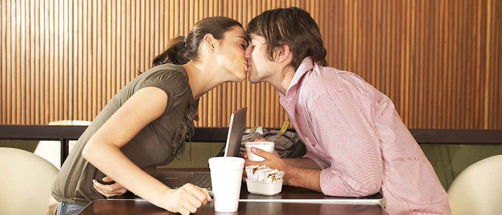 Man and woman kissing across the table as a symbol of what is dating