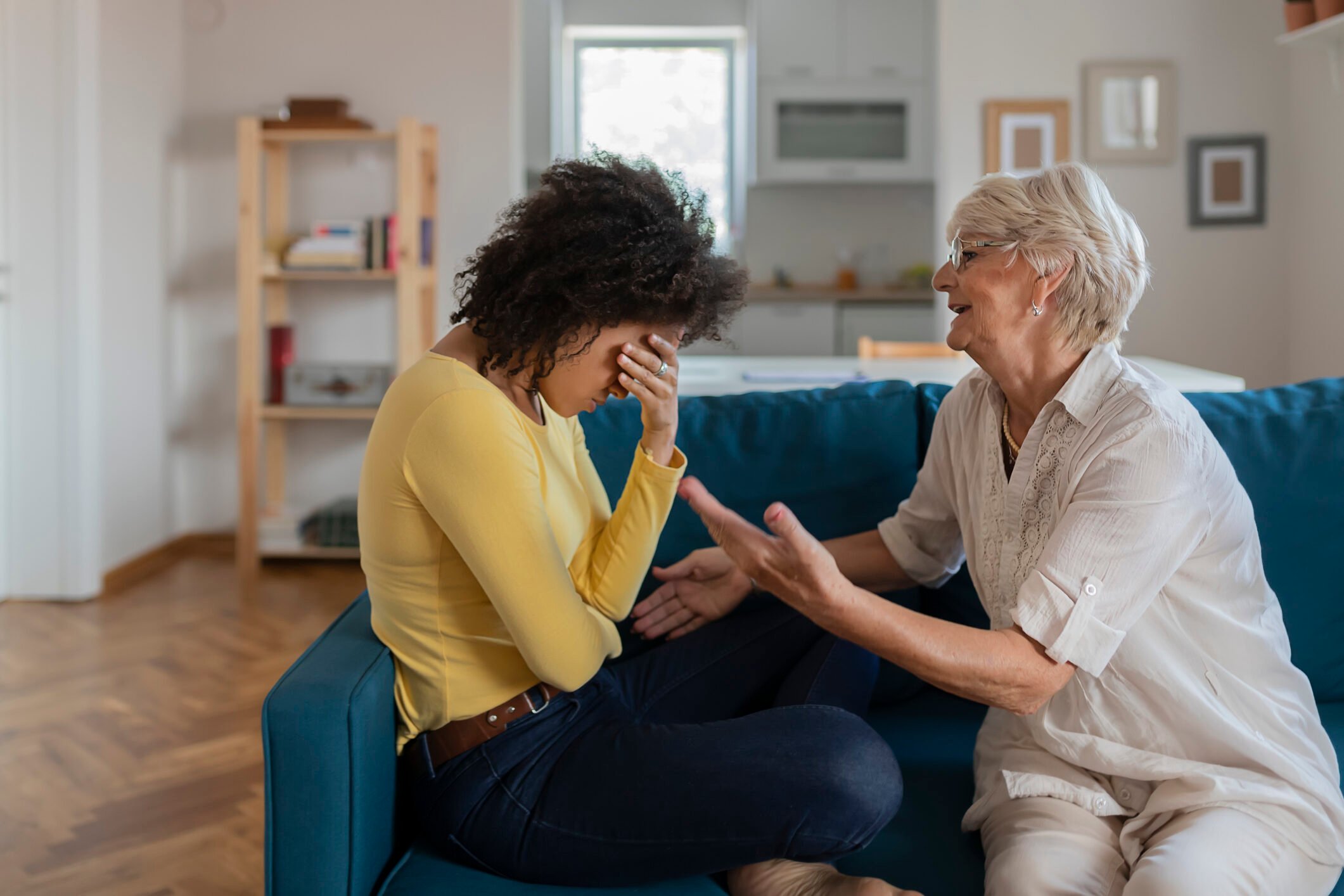 Older Mother Comforting Sad Adult Adopted Mixed Race Grown Daughter