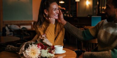 Man and woman in cafe, man caresses her face and she smiles as an example of the question does he like me