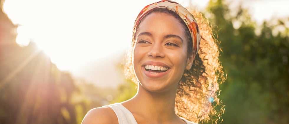 A woman with a huge smile standing under a beaming sun