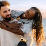 An older woman and a younger man having fun at the beach.