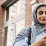 A woman looks at her cell phone and smiles, symbolizing Muslim dating