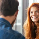 A women smiling and talking to a guy, showing how to ask a coworker out.