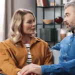 A couple sitting on their couch holding a conversation.