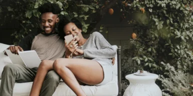 A couple sitting on a bench in the garden laughing together.