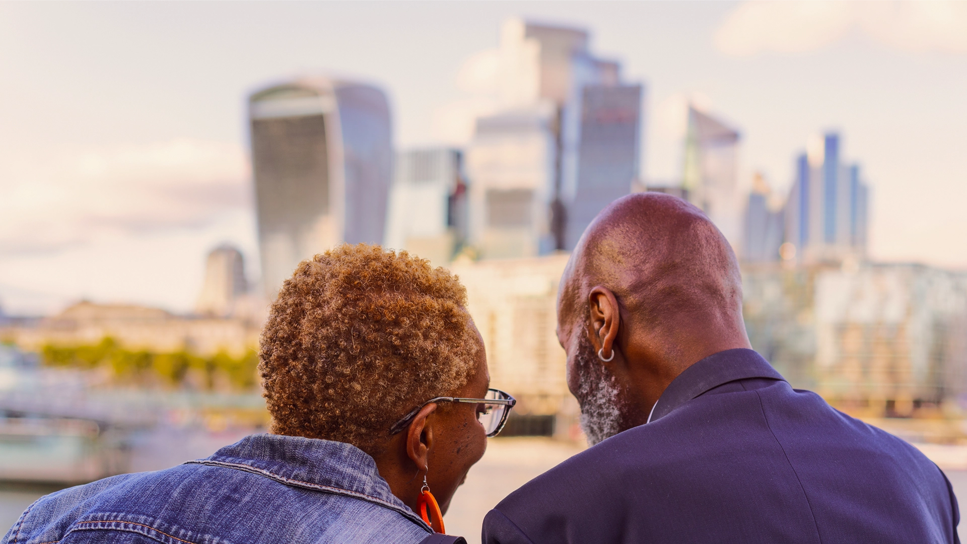 A couple is sitting together and enjoying the view of a city skyline.