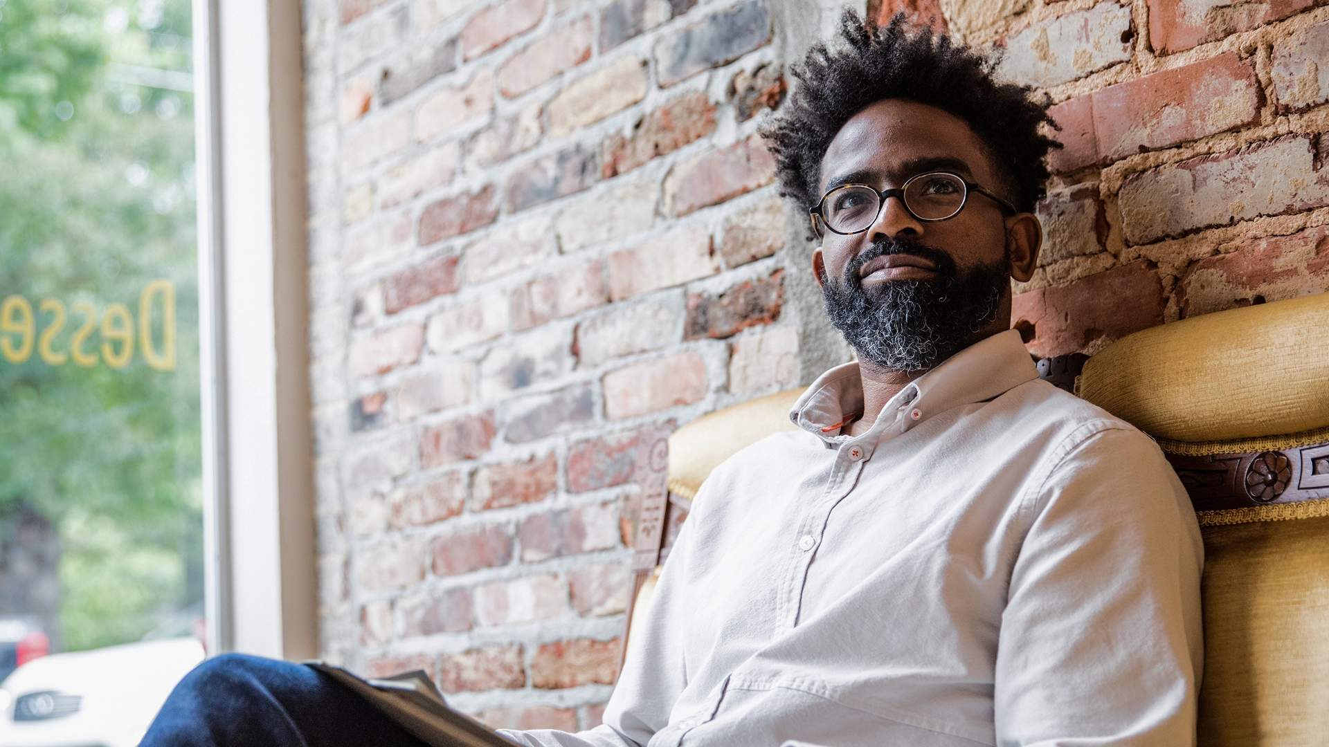 A man is sitting on a bench at a bus station.