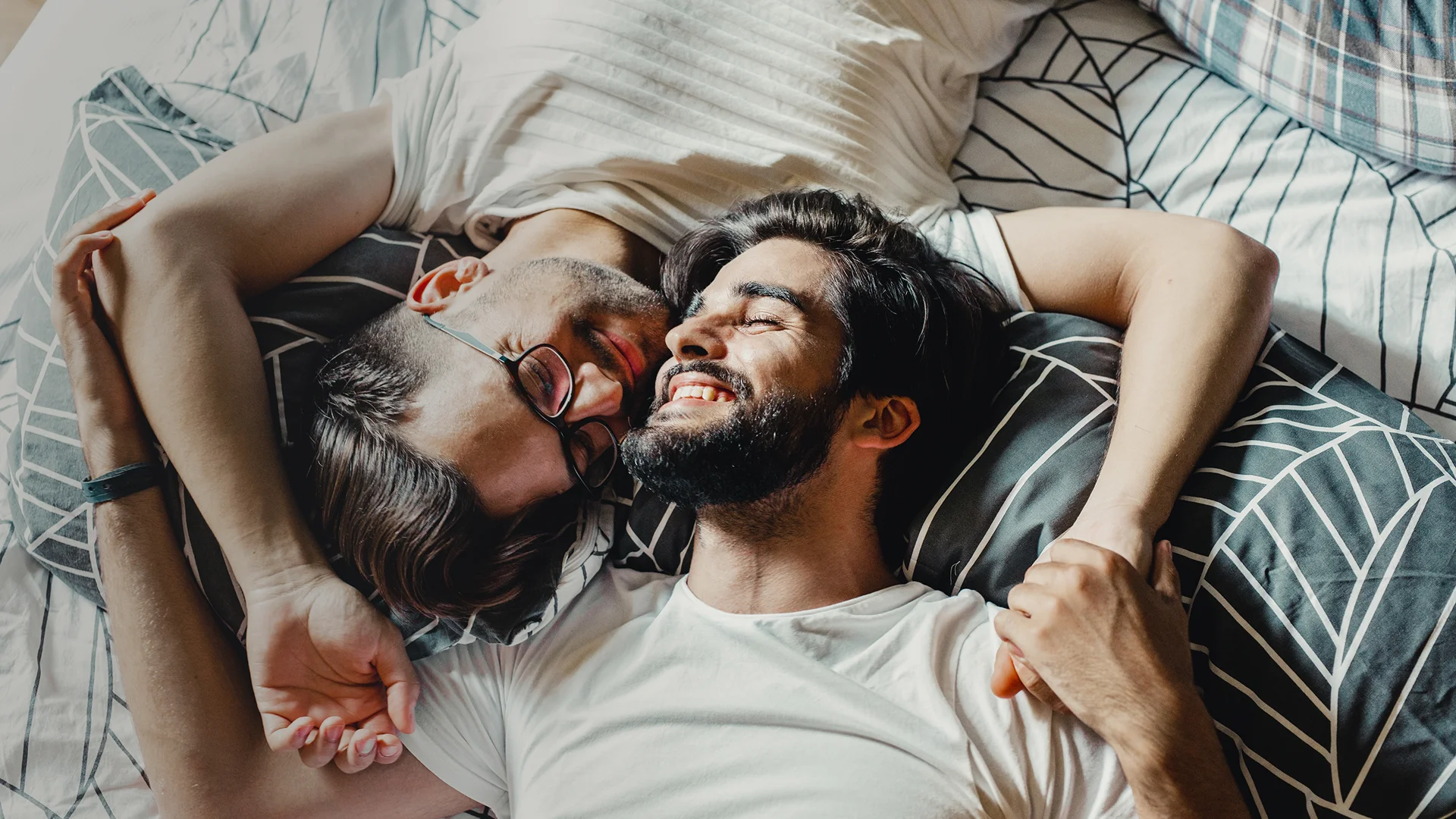 A gay couple lying in bed together.