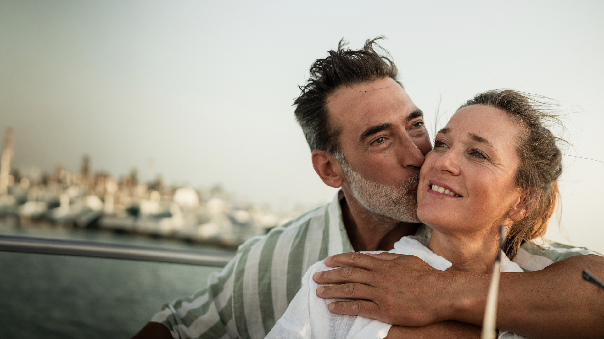 A man hugs a woman and kisses her on the cheek