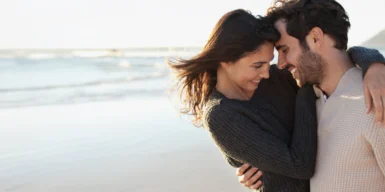 A man and a woman embrace on the beach as a symbol of eharmony