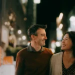 A japanese couple is walking on the street at night time.