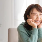 Korean Woman sitting at a table and smiling.